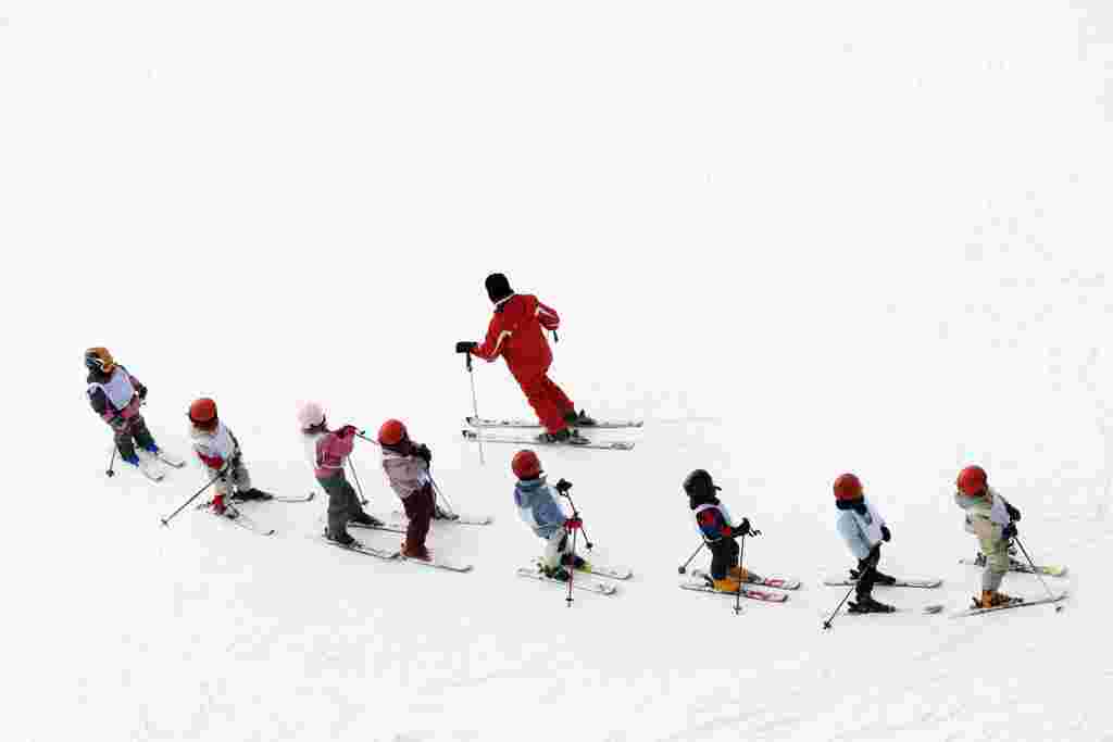 winter scene: kids learning to ski and their instructor. 