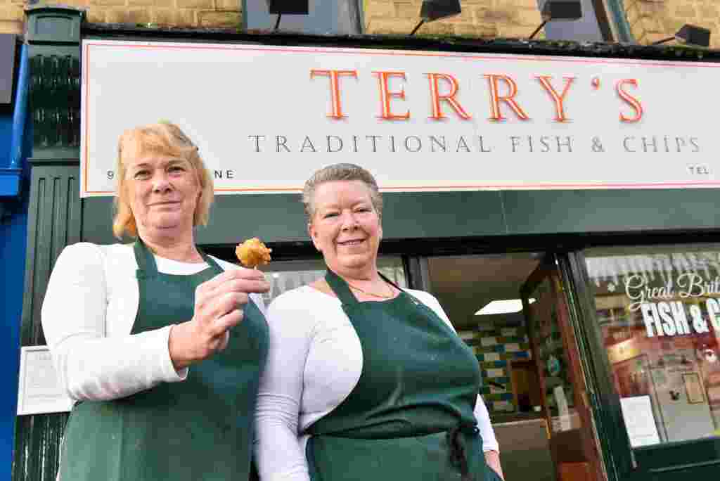 Andrea Long, 51, (right) sells battered Brussels sprouts at Terrys Traditional Fish and Chips in Huddersfield, West Yorks., with assistant Ann Hutchinson, 59 (left), December 06 2016. See Ross Parry story RPYSPROUT: Battered sprouts are proving a huge Christmas hit at a fish and chips shop.  People are flocking to Terry’s Traditional Fish and Chips in Huddersfield, Yorkshire, after it added the dish to its Christmas menu.  And they have been amazed at the reaction to the new ‘Yorkshire delicacy’,which is being given to customers as a Christmas gift.  The sprouts are the idea of manager Andrea Long.  But she has been stunned by the demand with 150 portions going out to regulars and they all say they love the battered sprouts, including children. Only two customers gave the sprouts the thumbs down.